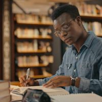 African man sitting inside a library alone doing research. Man working on a project. Young man doing research for a case. Lawyer working on a case