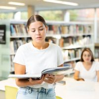 Intelligent Caucasian girl hold academic books in the college library